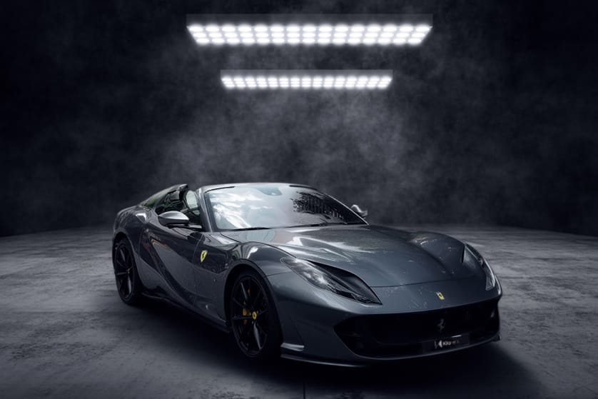 Voiture de sport grise décapotable photographiée dans un studio sombre, au design élégant et puissant