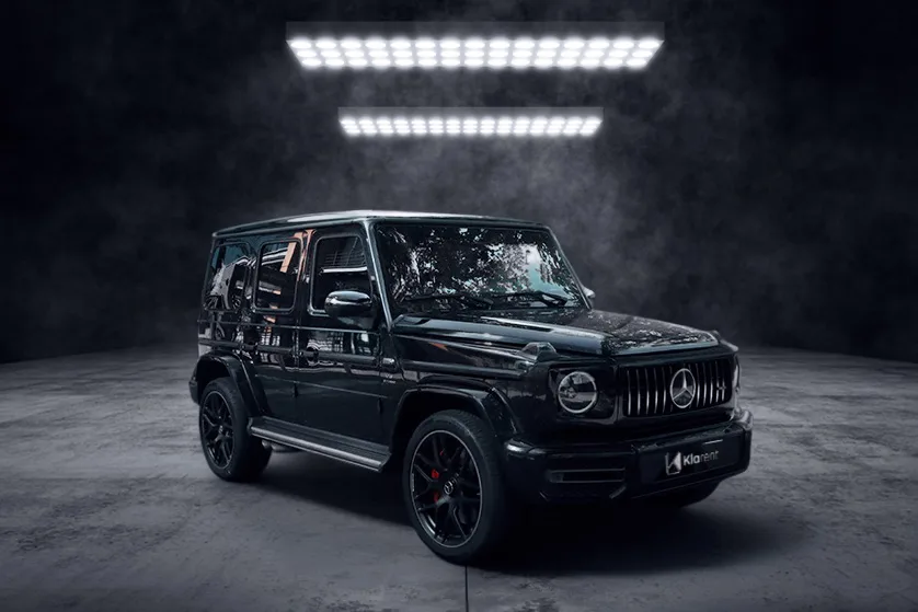 SUV noir haut de gamme photographié dans un studio sombre, au design robuste et luxueux
