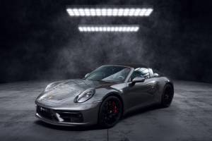 Voiture de sport grise décapotable photographiée dans un studio sombre, avec design élégant et moderne