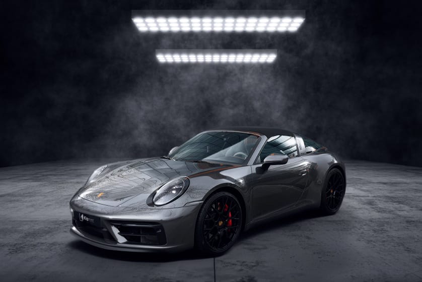 Voiture de sport grise décapotable photographiée dans un studio sombre, avec design élégant et moderne