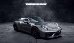 Voiture de sport grise décapotable photographiée dans un studio sombre, avec design élégant et moderne