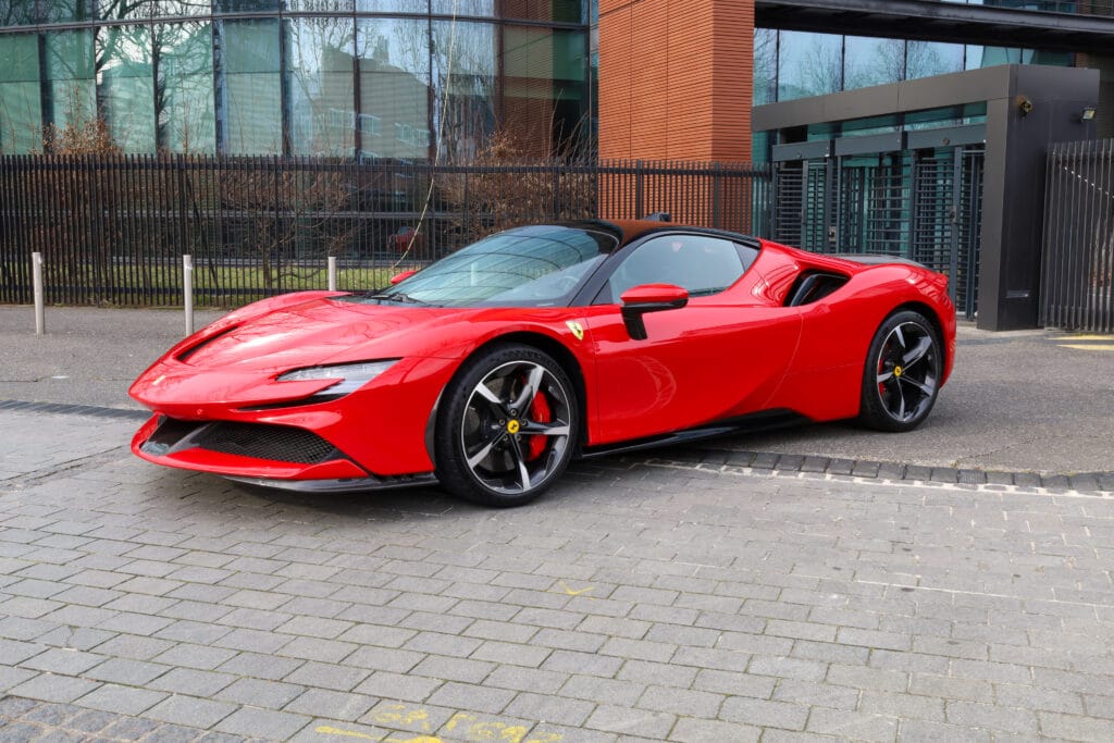 Vue avant d’une voiture de sport rouge photographiée dans un parc, véhicule au design aérodynamique et agressif