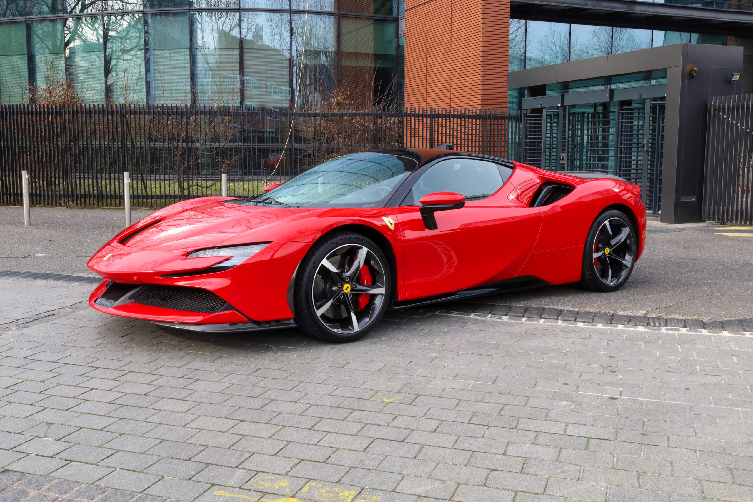 Vue avant d’une voiture de sport rouge photographiée dans un parc, véhicule au design aérodynamique et agressif