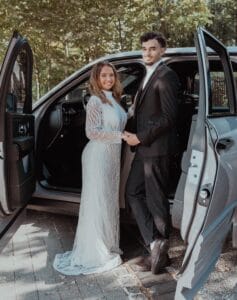Mariés élégants devant une Rolls Royce Cullinan Black Badge lors d’un mariage de luxe